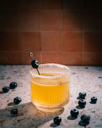 Close-up of whisky sour cocktail in tumbler glass with blueberries on stone counter