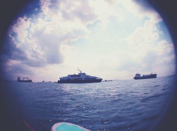 Boat sailing in sea against cloudy sky