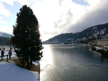 Scenic view of lake by snowcapped mountains against sky