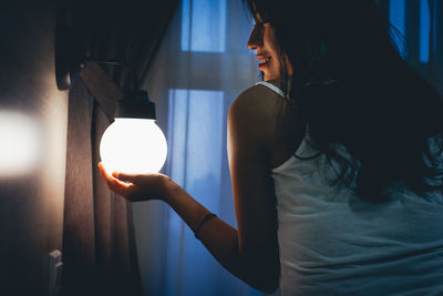 Woman holding illuminated light bulb