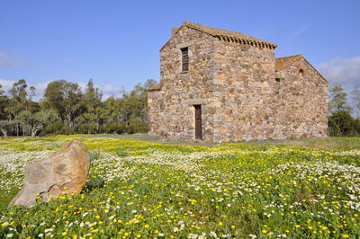 Church by field against sky on sunny day