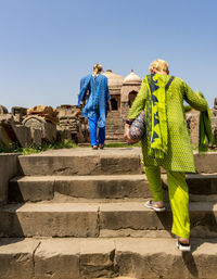 Rear view of people walking on steps against sky
