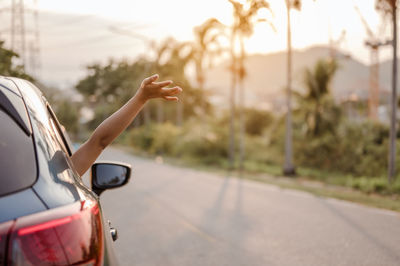 Cropped image of woman leaning hand out of car window