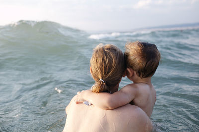 Rear view of mother and son at beach 