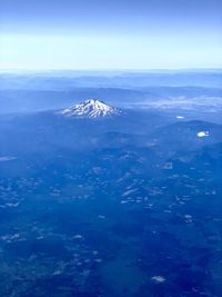 Aerial view of snowcapped mountains against blue sky