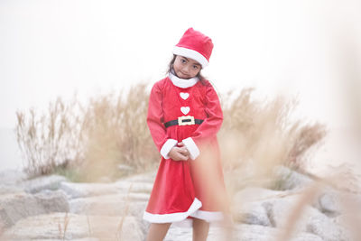 Portrait of cute girl standing against red during winter