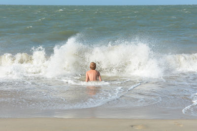 Rear view of shirtless man in sea