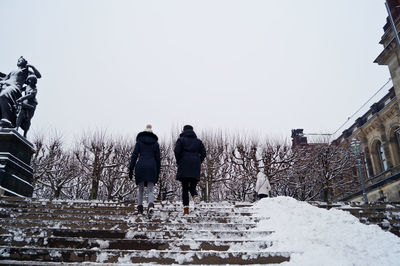 Rear view of people walking on snow covered landscape