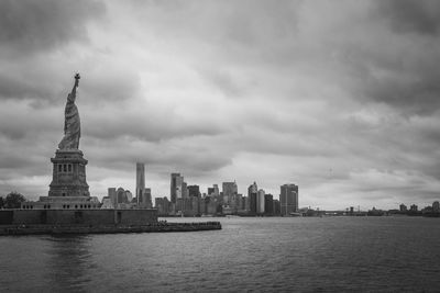 Statue of liberty and buildings against cloudy sky