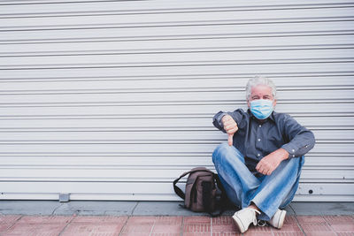 Portrait of a young man sitting against closed shutter