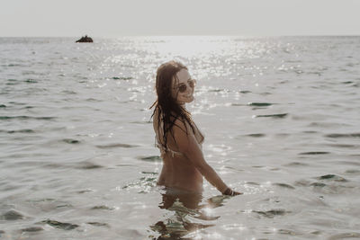 Smiling sensuous woman standing in sea at beach