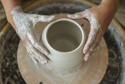 Cropped hands of woman making pottery in workshop