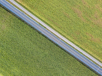 High angle view of railroad track and road amidst field