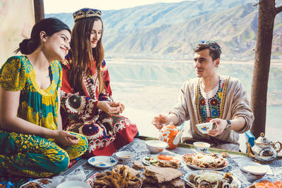 Smiling young woman holding food while sitting on table