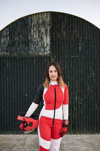 Young female skydiver posing in a black wall with helmet and gloves