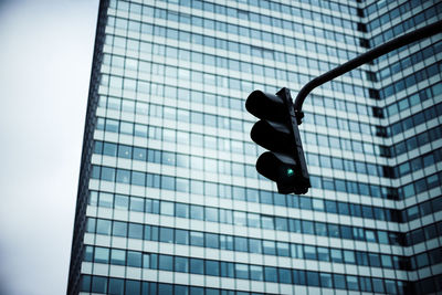 Low angle view of stoplight against modern building in city