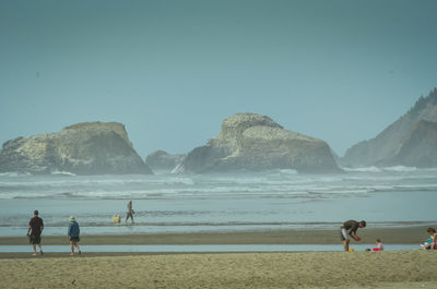 People on beach against clear sky