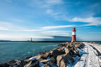 Lighthouse by sea against sky