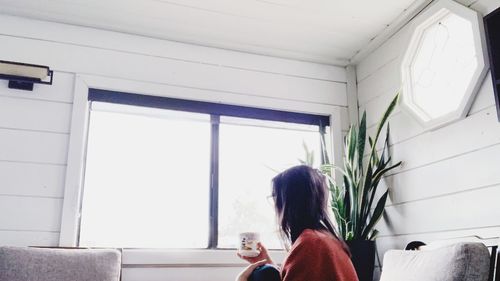 Rear view of woman looking through window