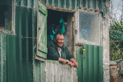 Portrait of happy man standing by window