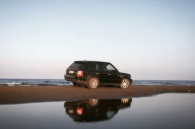 Vintage car on beach against clear sky