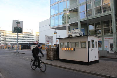 Man riding bicycle on street against buildings in city