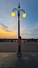 Man standing on street against sky during sunset