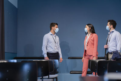 Colleagues with protective face mask talking in board room at conference