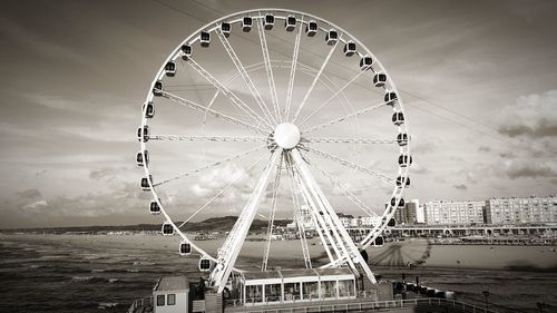 Ferris wheel in amusement park against cloudy sky