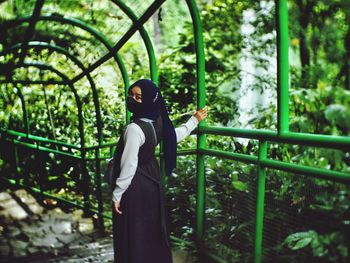 Rear view of woman standing against trees