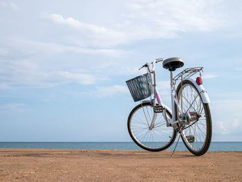 Bicycle on beach against sky