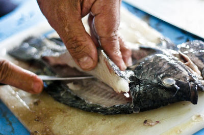 Cropped image of hands filleting fish at market