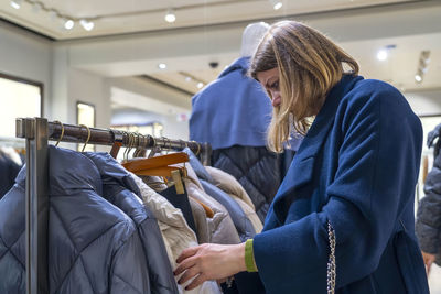 Portrait of happy woman customer chooses jacket in clothing store