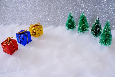 Christmas trees and multi colored gift boxes on snow