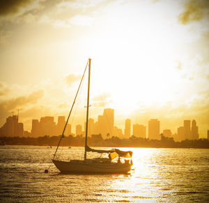 Sailboats in sea against sky during sunset