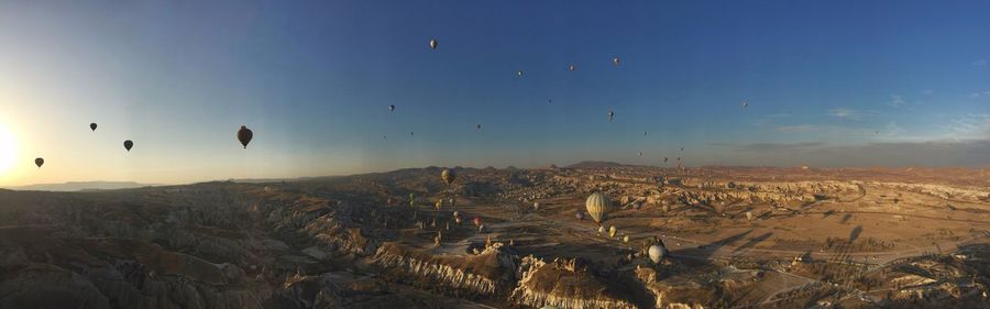 Hot air balloons flying over landscape against sky