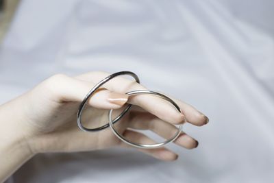 Cropped hand of woman holding bangles on bed at home