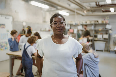 Portrait of confident female teacher with pupils in technology classroom at school