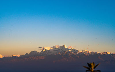 Scenic view of snowcapped mountains against clear sky during sunset