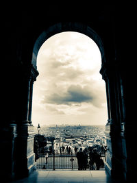 People at historical building against cloudy sky