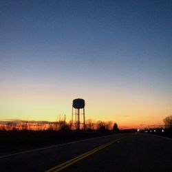 Silhouette road against clear sky at sunset