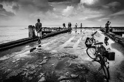 Panoramic view of people on beach against cloudy sky