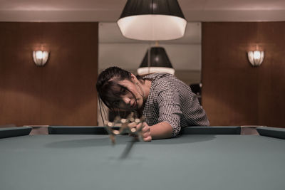 Young woman leaning on pool table