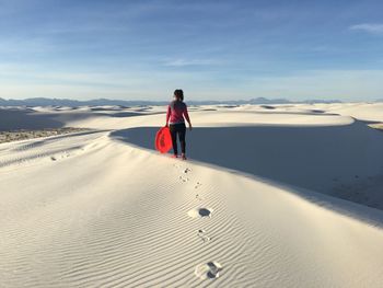 Rear view of woman standing on sand dune in desert