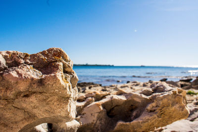 Rocks on beach against clear blue sky