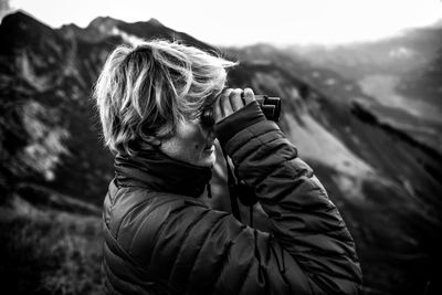 Man holding binoculars against mountain