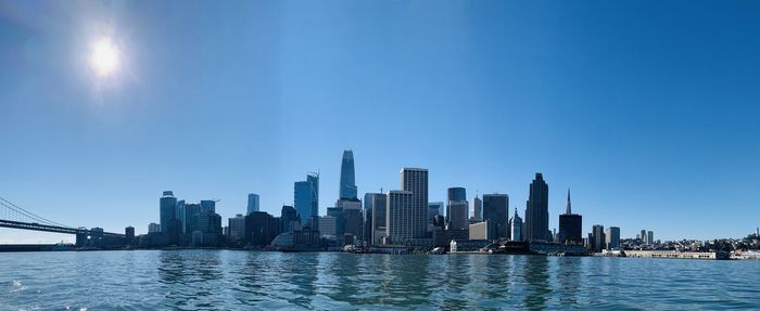 Modern buildings by river against sky in city