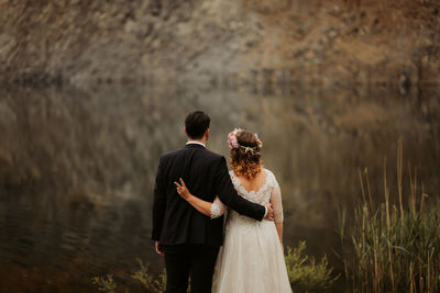 Rear view of couple standing on shore against sky