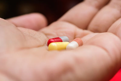 Close-up of hand holding multi colored capsules