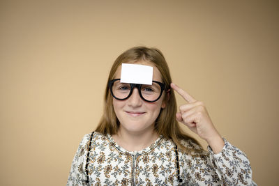 Portrait of young woman wearing sunglasses against yellow background